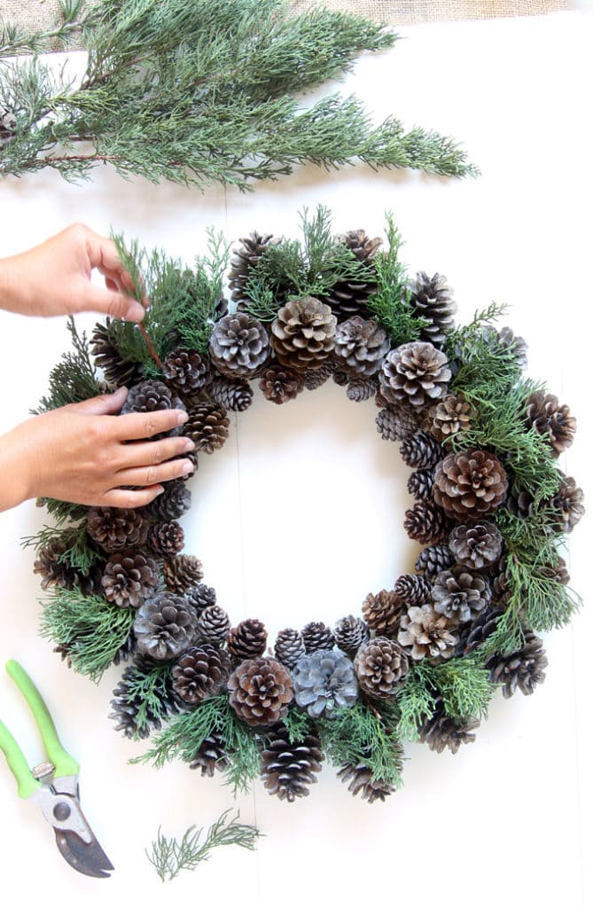 adding conifer greens to DIY pinecone wreath
