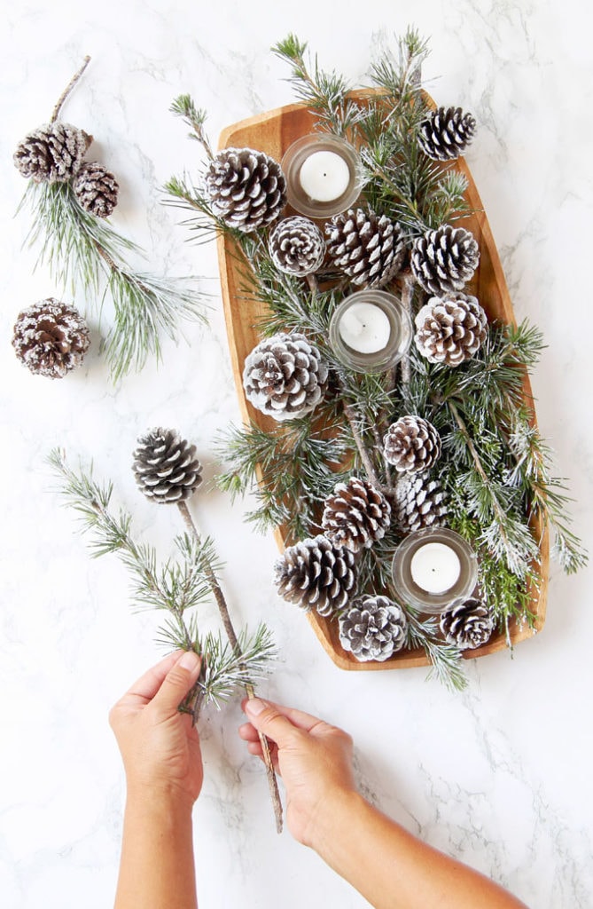 centerpiece with candles and DIY snow covered pine cones & branches in wood tray