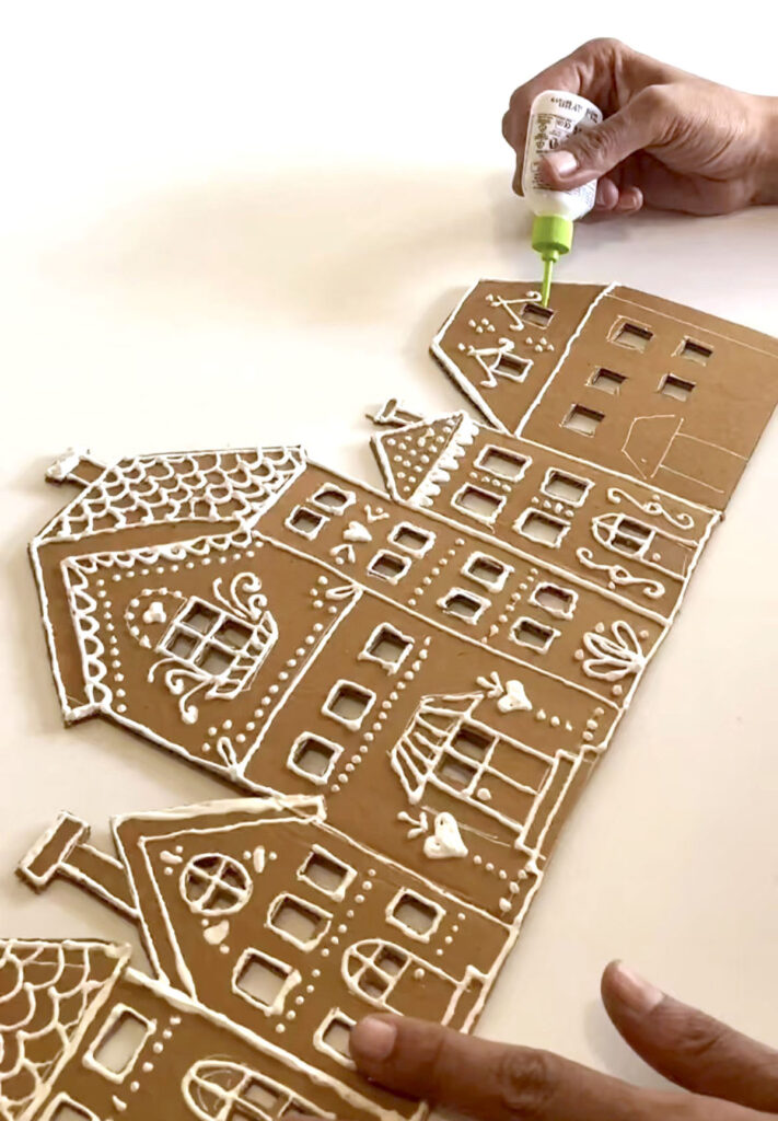 Use dimensional puff paint to decorate cardboard houses 